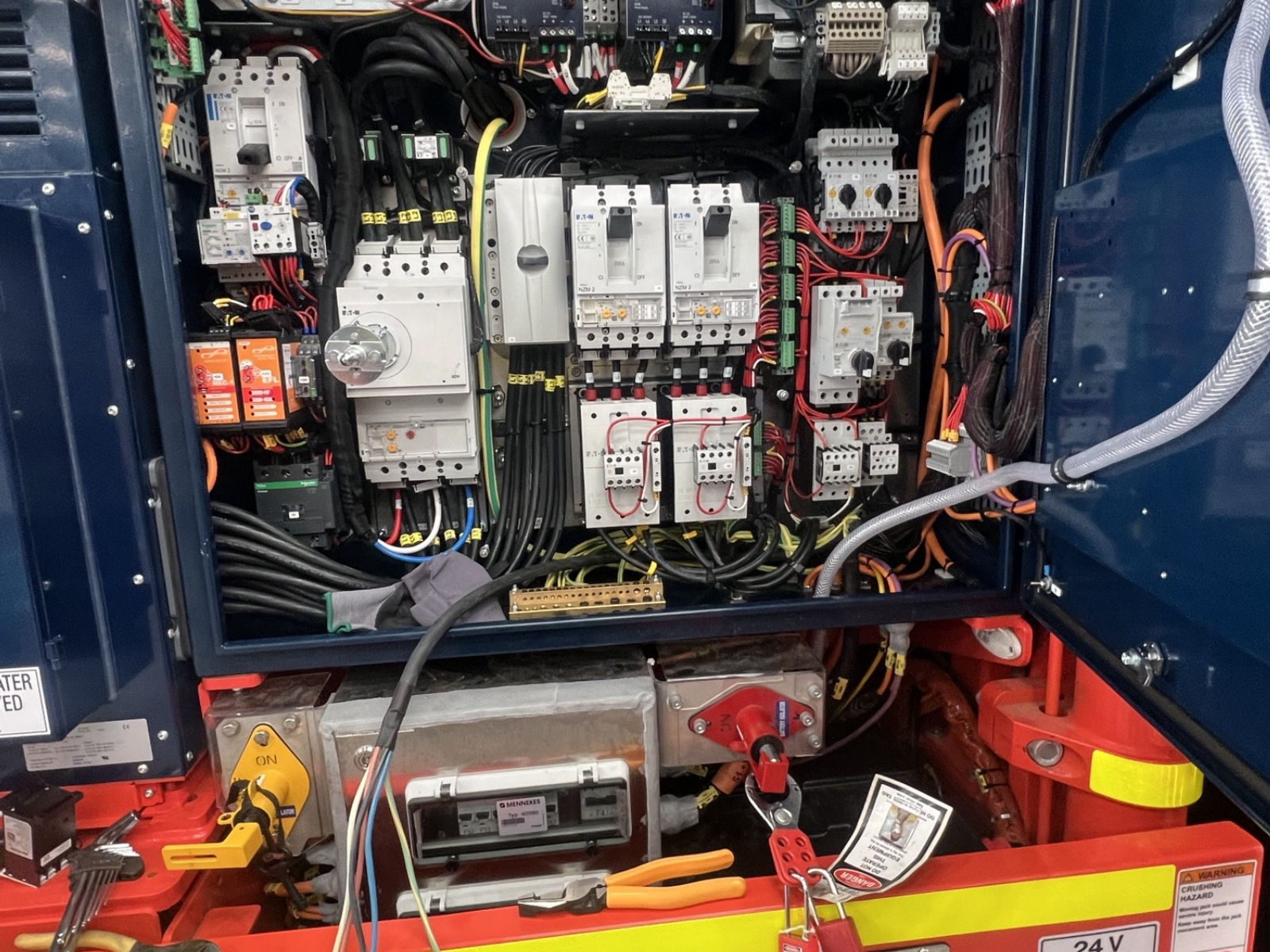 Underground drill rig control panel opened for work with an isolation lock and danger tag applied