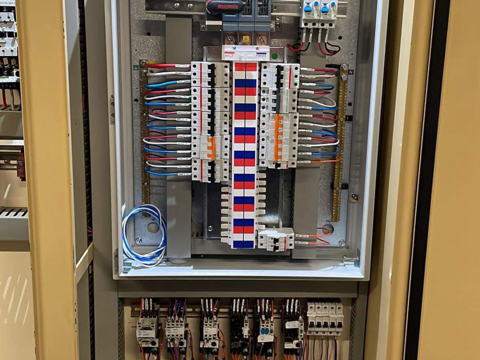 Switchboard distribution section with phase-marked circuit breakers, neutral bar and contactors below